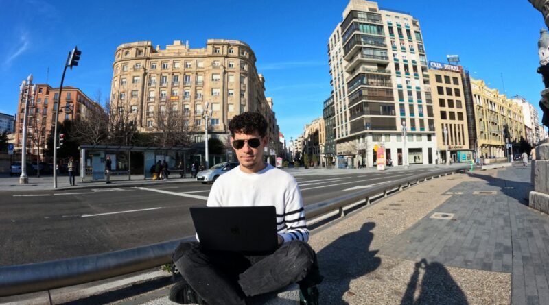 un joven trabaja con su laptop en una calle en España