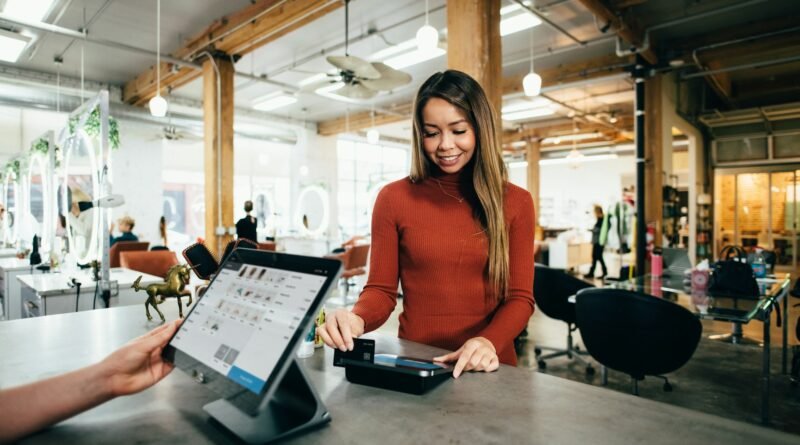 una mujer pasa su tarjeta en un punto de venta para pagar un servicio