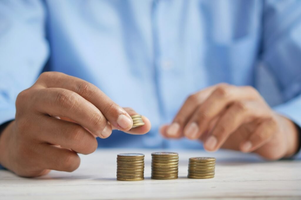 Una persona apila monedas en una mesa.