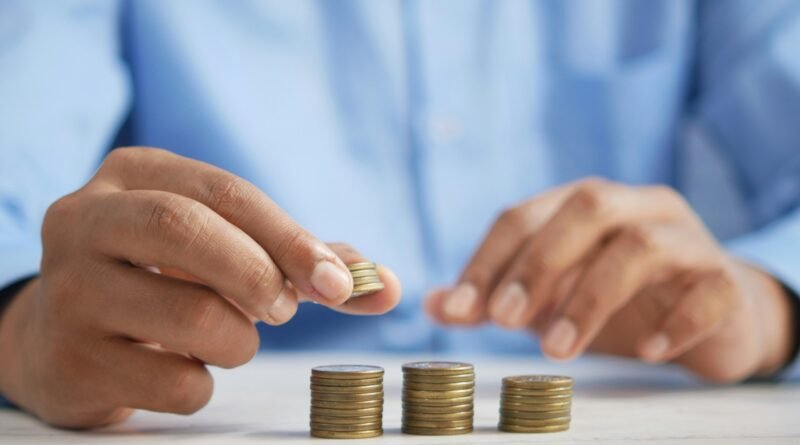 Una persona apila monedas en una mesa.